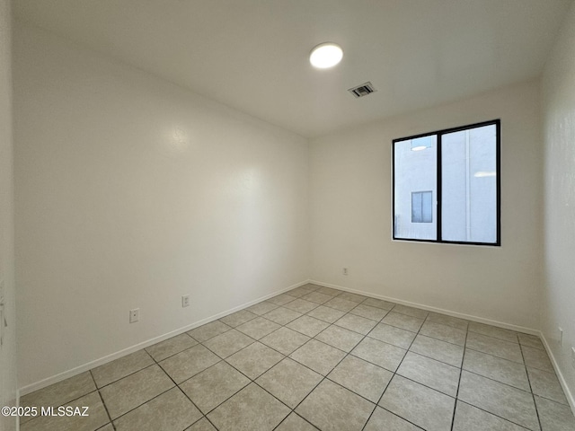 empty room featuring baseboards, visible vents, and light tile patterned floors