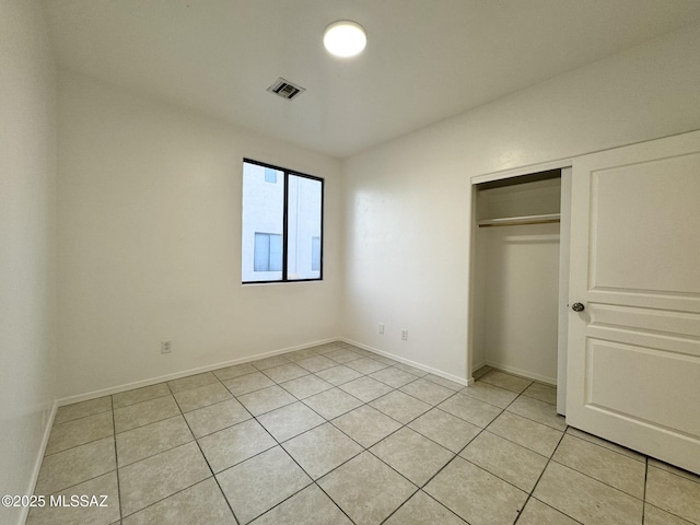 unfurnished bedroom featuring visible vents, baseboards, light tile patterned floors, and a closet