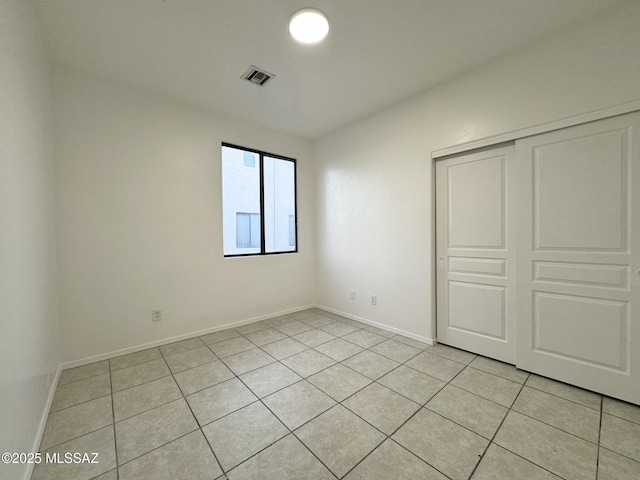 unfurnished bedroom with light tile patterned floors, baseboards, a closet, and visible vents