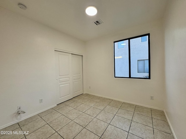 unfurnished bedroom with baseboards, light tile patterned floors, and a closet