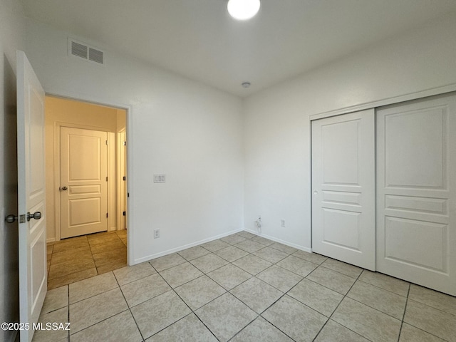 unfurnished bedroom featuring visible vents, baseboards, light tile patterned floors, and a closet