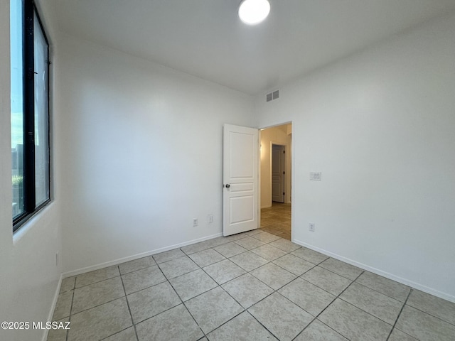 empty room featuring light tile patterned floors, baseboards, and visible vents