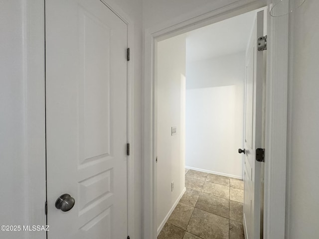 corridor featuring baseboards and stone finish flooring
