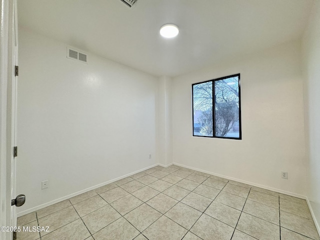 empty room with light tile patterned floors, baseboards, and visible vents