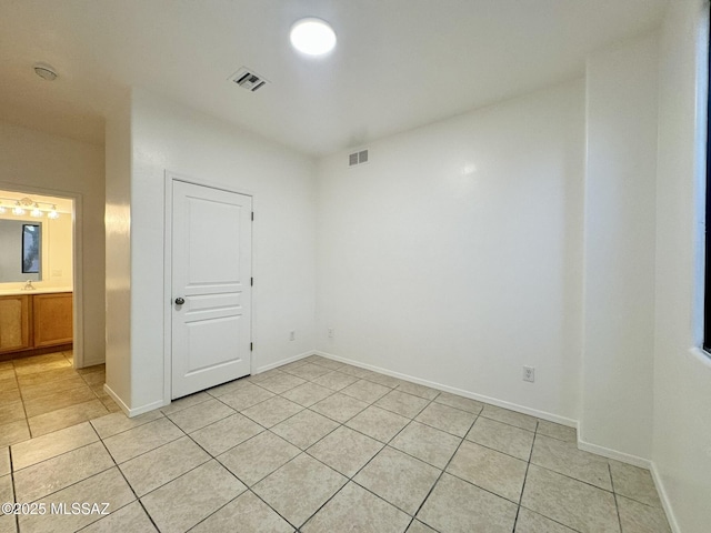 empty room featuring visible vents, a sink, and light tile patterned flooring