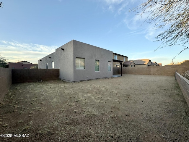 back of house featuring a fenced backyard and stucco siding