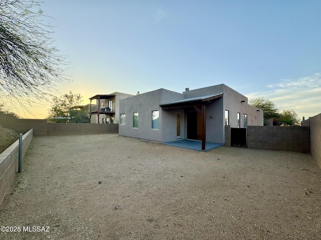 back of property at dusk with a patio, a fenced backyard, and stucco siding
