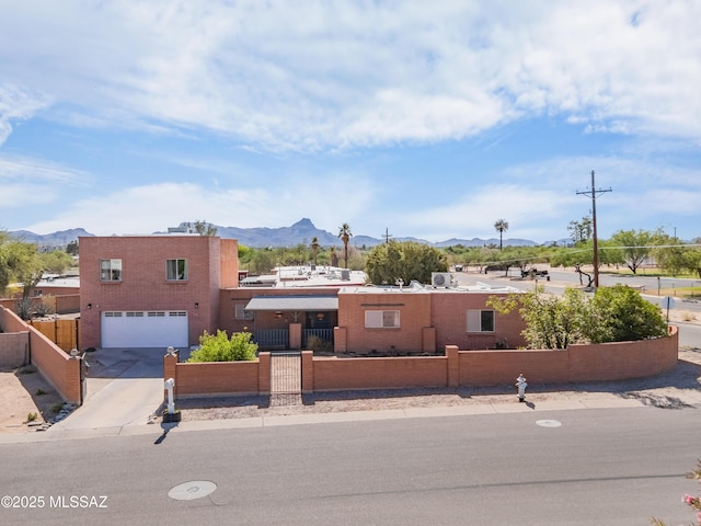 7571 N Rae Ave, Tucson, AZ 85741 - pueblo-style house with a fenced front yard, a mountain view, a garage, and concrete driveway