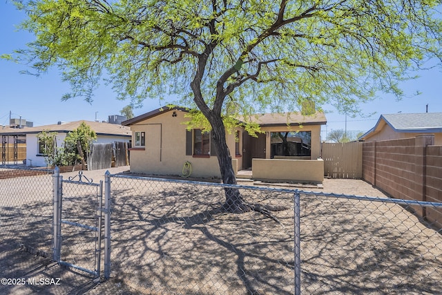 rear view of house with a fenced backyard, a gate, and stucco siding
