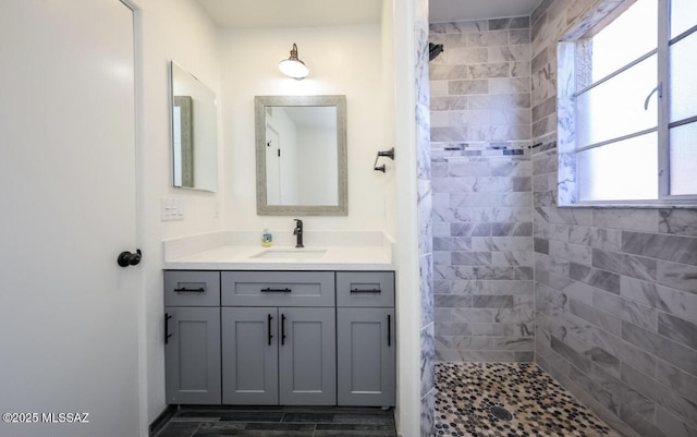 bathroom with plenty of natural light, tiled shower, and vanity
