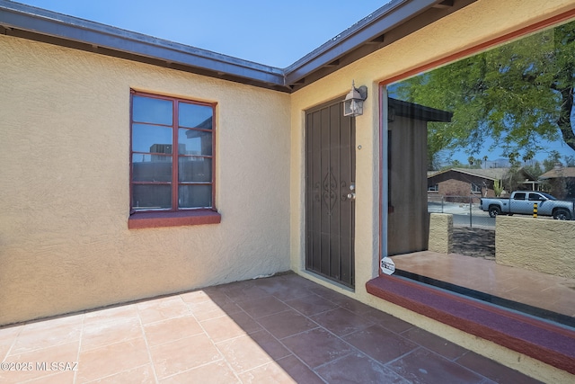doorway to property featuring a patio area and stucco siding