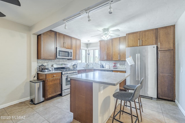 kitchen featuring a ceiling fan, tasteful backsplash, a sink, track lighting, and stainless steel appliances