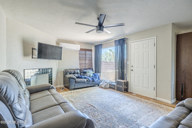 living area featuring baseboards, ceiling fan, a wall mounted AC, and wood finished floors