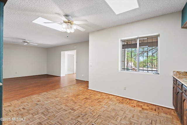 1011 N Placita Yoas, Green Valley, AZ 85614 - unfurnished room featuring a skylight, a ceiling fan, a textured ceiling, baseboards, and parquet flooring