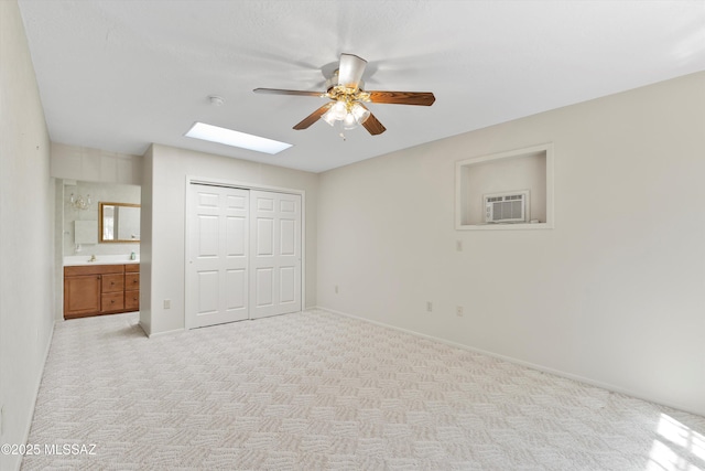 1011 N Placita Yoas, Green Valley, AZ 85614 - unfurnished bedroom with a skylight, light carpet, a closet, a wall mounted AC, and baseboards