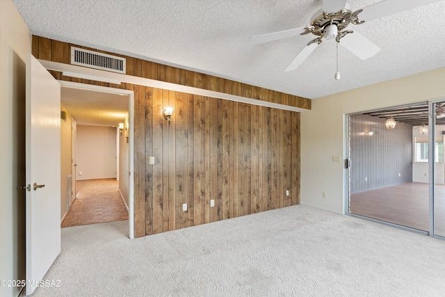1011 N Placita Yoas, Green Valley, AZ 85614 - spare room featuring carpet, wood walls, a ceiling fan, and a textured ceiling