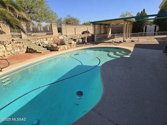 view of pool with fence, a patio, a shed, a fenced in pool, and an outbuilding