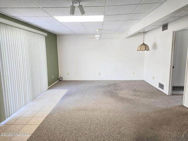 empty room with a ceiling fan, light colored carpet, a drop ceiling, and visible vents