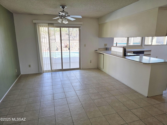kitchen with light tile patterned floors, plenty of natural light, a ceiling fan, and a textured ceiling
