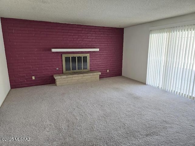 unfurnished living room featuring a brick fireplace, carpet flooring, and a textured ceiling