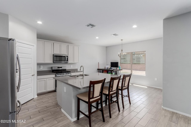10157 N Sand Sage Trl, Marana, AZ 85653 - kitchen with visible vents, light wood-type flooring, a sink, an inviting chandelier, and stainless steel appliances