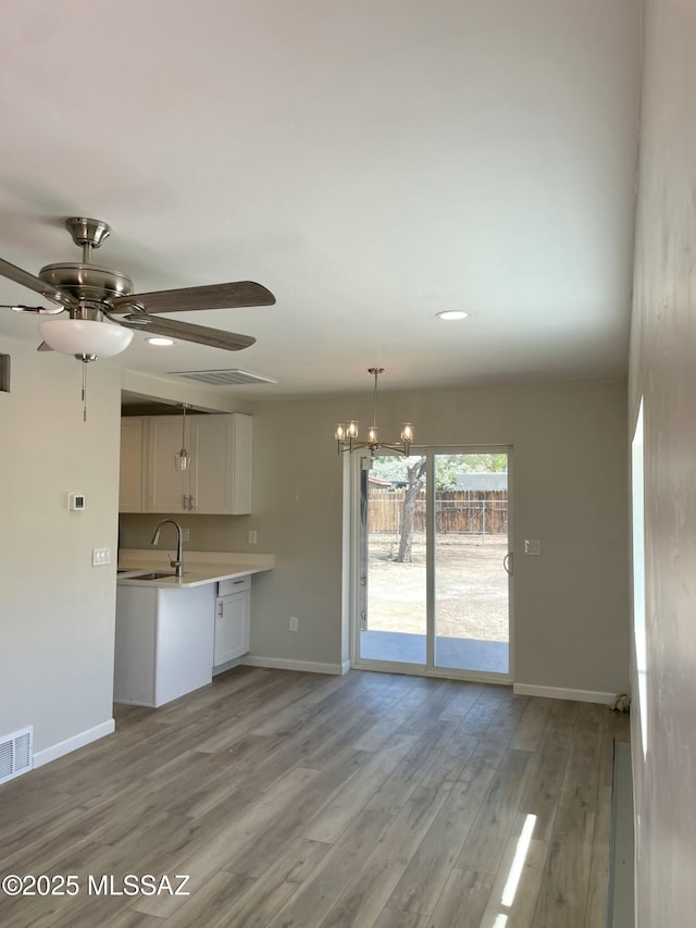 3923 E 17th St, Tucson, AZ 85711 - unfurnished living room with baseboards, a sink, a chandelier, a ceiling fan, and light wood-style floors