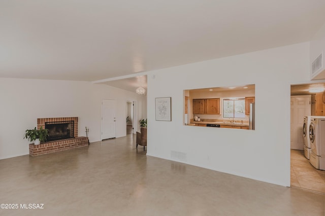5417 E 3rd St, Tucson, AZ 85711 - unfurnished living room featuring independent washer and dryer, a sink, a brick fireplace, concrete floors, and visible vents