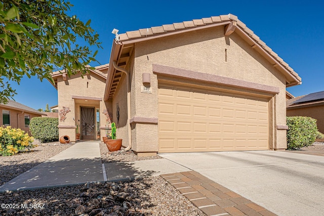 view of front of house featuring a tiled roof, a garage, driveway, and stucco siding