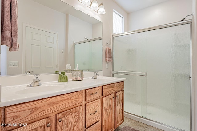 bathroom featuring double vanity, a shower stall, a sink, and tile patterned flooring