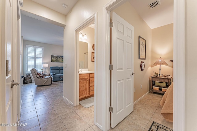 hallway featuring light tile patterned floors, baseboards, and visible vents