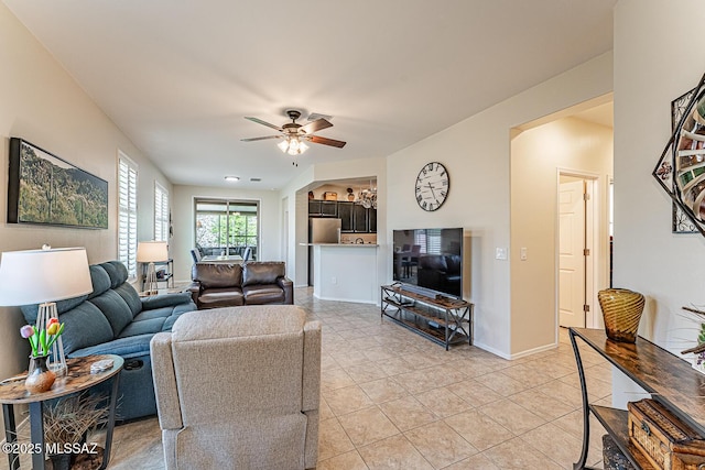 living area featuring baseboards, ceiling fan, and light tile patterned floors