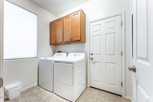 laundry room featuring cabinet space, light tile patterned floors, washer and dryer, and a wealth of natural light