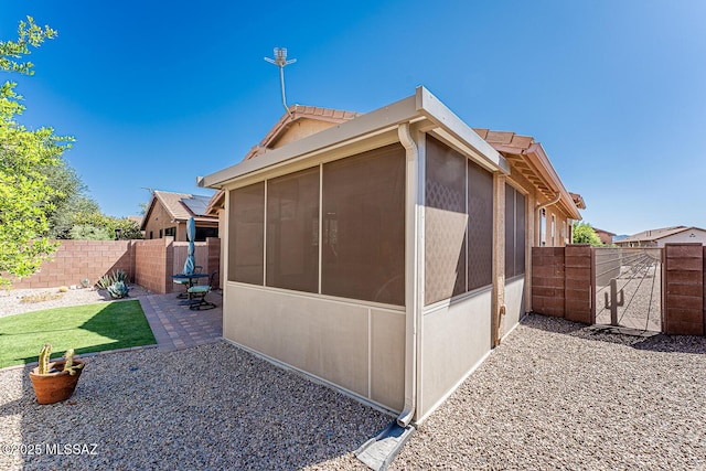 view of property exterior with a sunroom, a fenced backyard, and a patio area