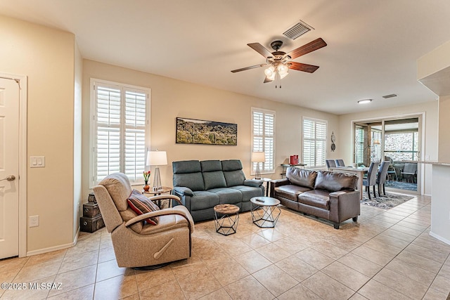 living area with light tile patterned floors, baseboards, ceiling fan, and visible vents