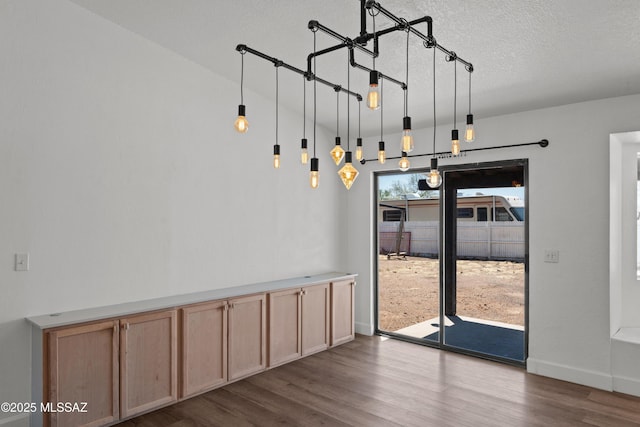 unfurnished dining area featuring baseboards, dark wood-style flooring, and a textured ceiling