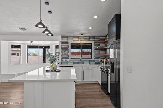kitchen with a kitchen island, visible vents, black electric range, and wood finished floors