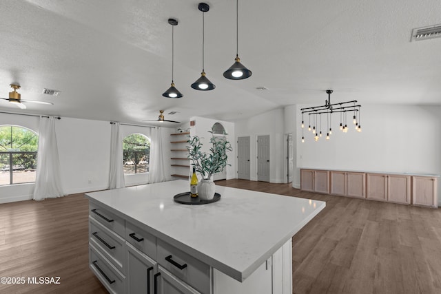 kitchen with visible vents, open floor plan, and ceiling fan with notable chandelier