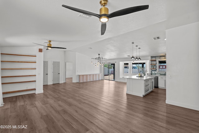 unfurnished living room featuring visible vents, ceiling fan with notable chandelier, wood finished floors, and vaulted ceiling