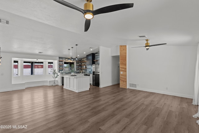 unfurnished living room with visible vents, a ceiling fan, light wood-style floors, and vaulted ceiling