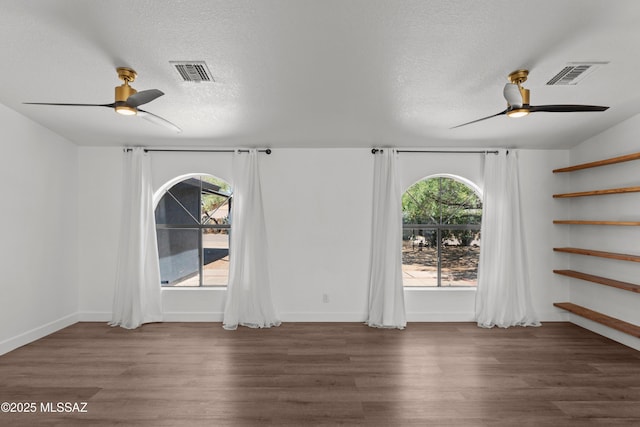 empty room featuring a wealth of natural light, ceiling fan, and visible vents