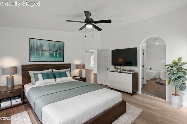 bedroom with arched walkways, baseboards, wood finished floors, and visible vents