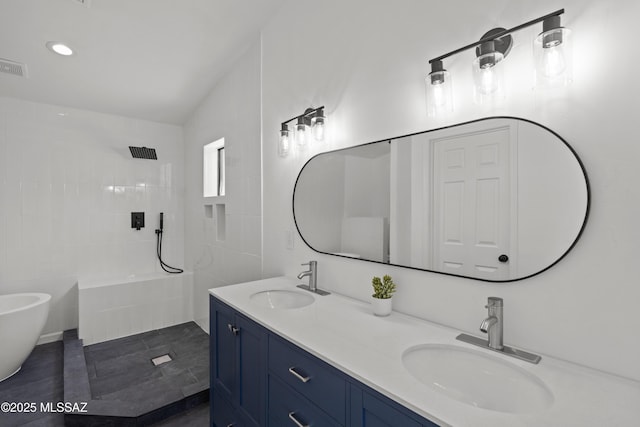 bathroom with double vanity, a sink, and tiled shower