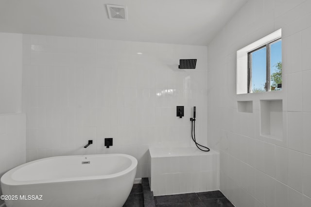 full bath featuring visible vents, a freestanding bath, tile walls, a tile shower, and tile patterned floors