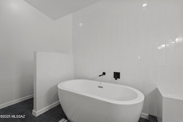 bathroom with a freestanding tub, tile patterned floors, and tile walls