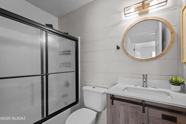 full bath featuring vanity, combined bath / shower with glass door, and toilet