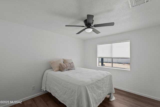 bedroom featuring ceiling fan, baseboards, visible vents, and wood finished floors