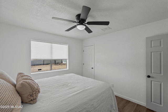 bedroom featuring a ceiling fan, baseboards, visible vents, and wood finished floors