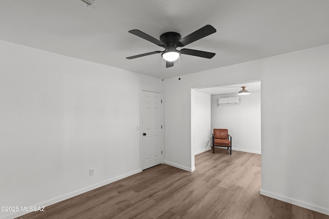 unfurnished bedroom featuring baseboards, a ceiling fan, an AC wall unit, and wood finished floors