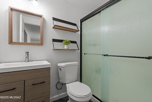 bathroom featuring toilet, baseboards, a shower with shower door, and vanity