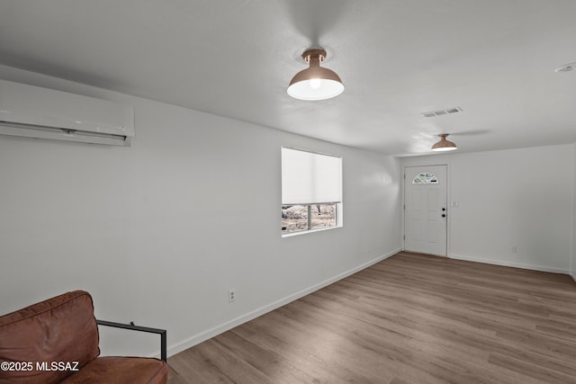 foyer featuring an AC wall unit, baseboards, visible vents, and wood finished floors